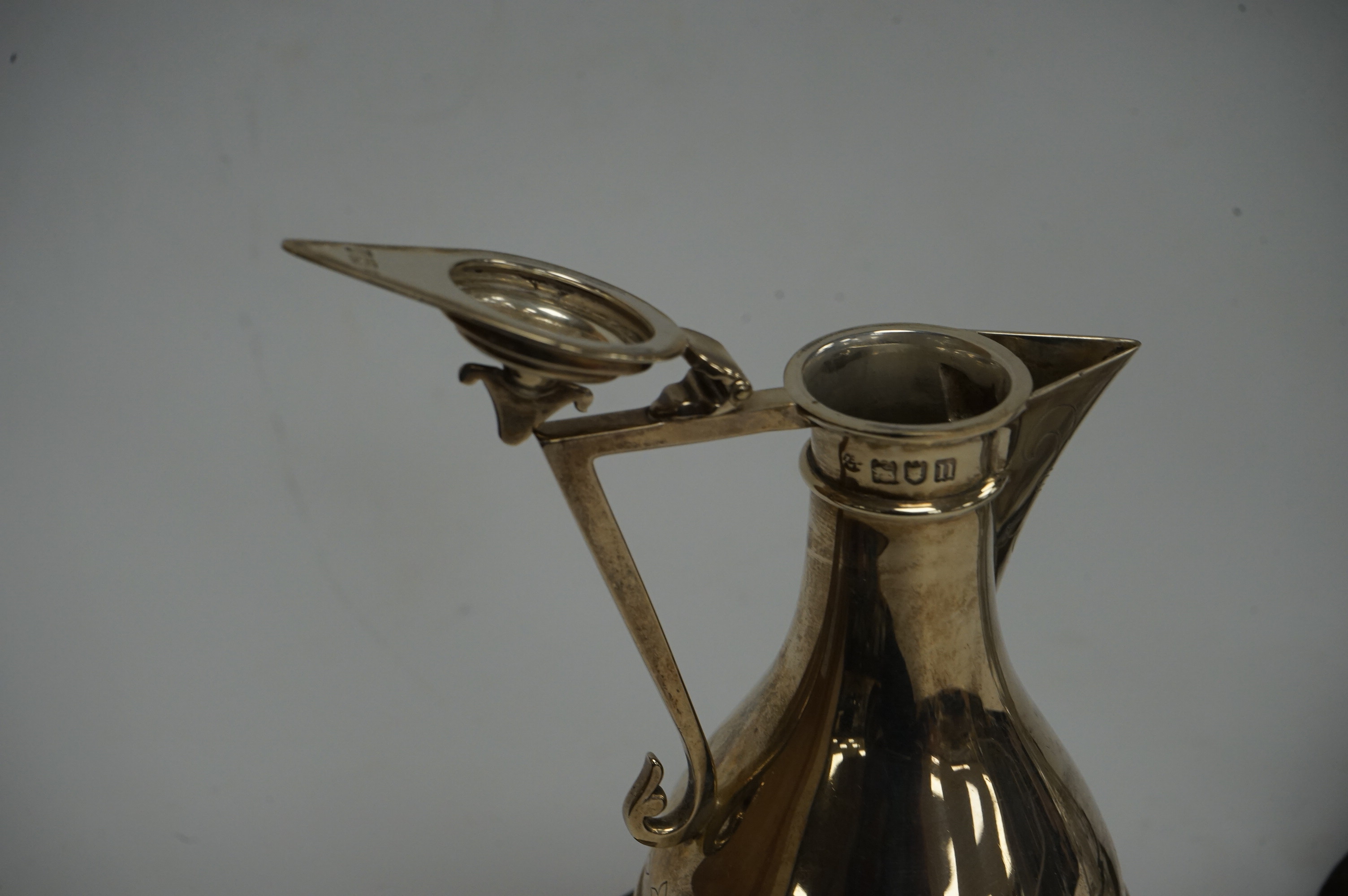 An Edwardian silver communion jug, by James Deakin & Sons, London, 1908, 15.2cm, together with a late Victorian repousse silver cruet stand with two glass bottles and stoppers, James Dixon & Sons, Sheffield, 1897 and a c